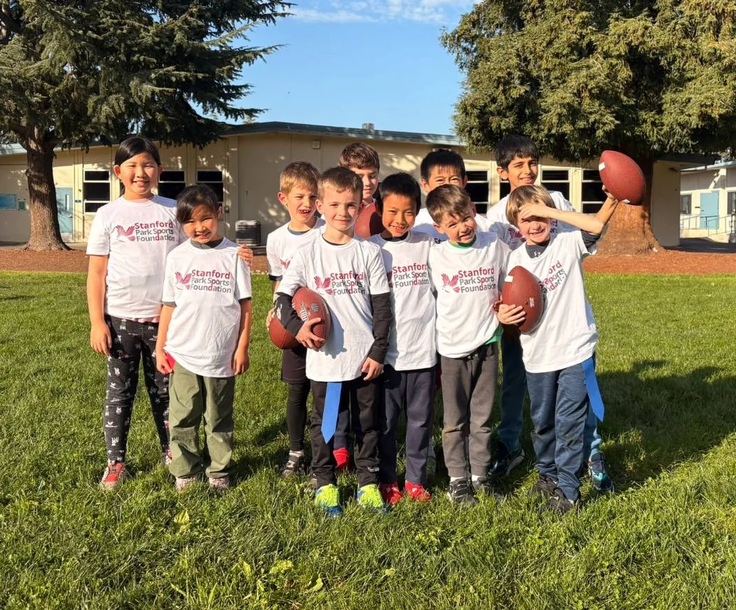 Flag football team in Stanford Park Sports Foundation shirts smiling on their school field after school