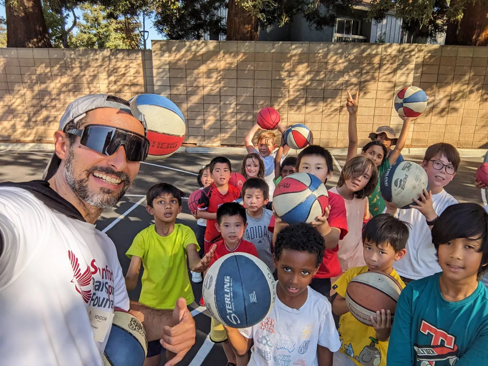 Stanford Park Sports coach and students with basketballs on the school blacktop